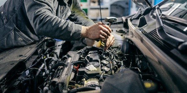 Close up of a mechanic fixing car under the hood with tools at garage.